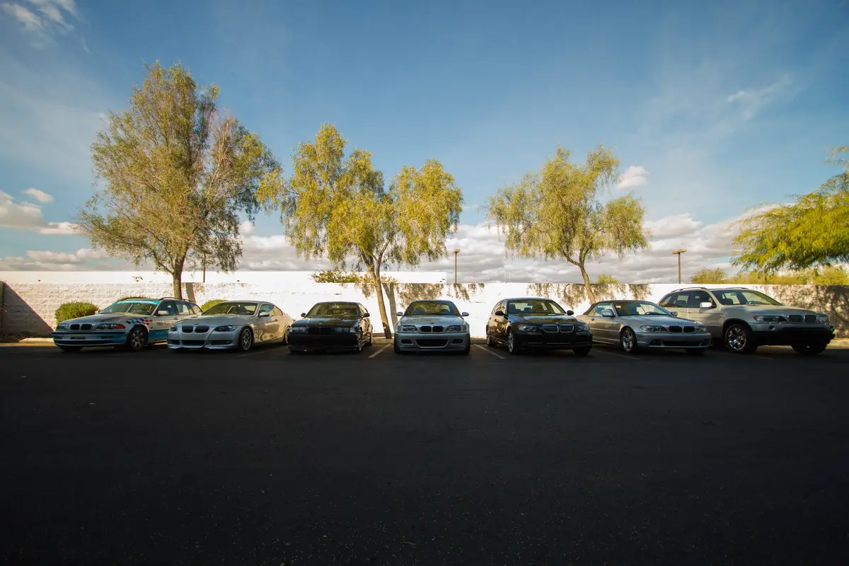 Seven customer and team BMWs, including an Ultimate Auto Works E36 race car, lined up under the Arizona sky